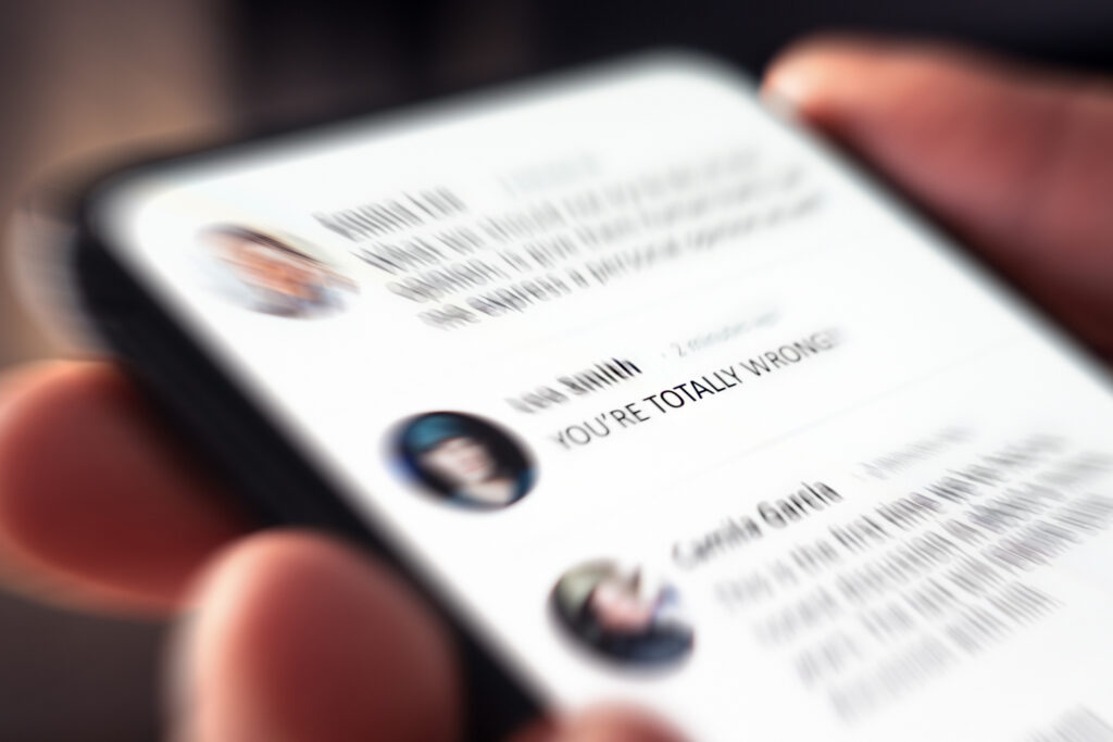 Controversy, online anger and troll or hate comment on social media. Debate, fight and bad dialog on news feed. Cyber bully and hater posting mean negative message. Reading mobile phone screen.